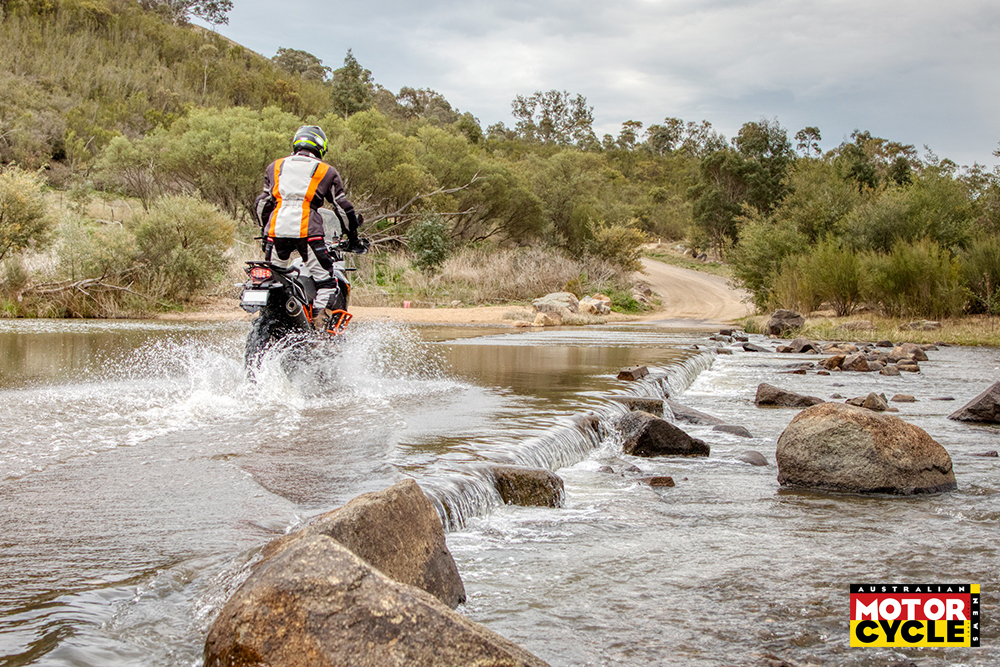 Guy on an adventure motorcycle crossing a river